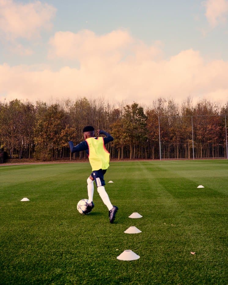 A player in a yellow bib running cone drills
