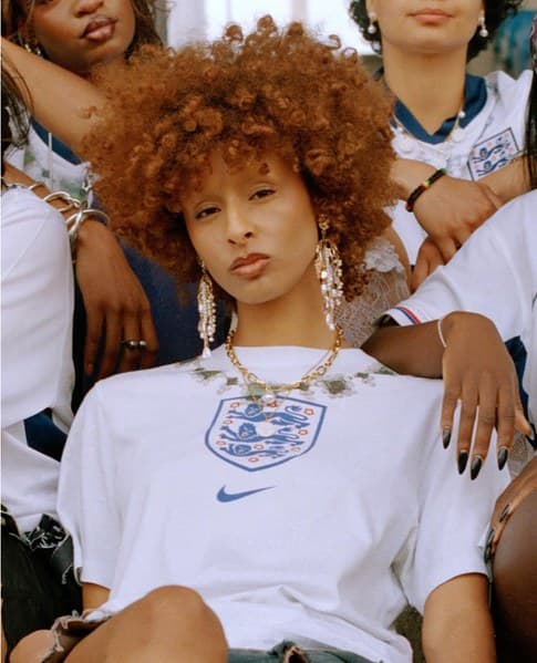 Woman with copper curls in an England shirt, surrounded by friends