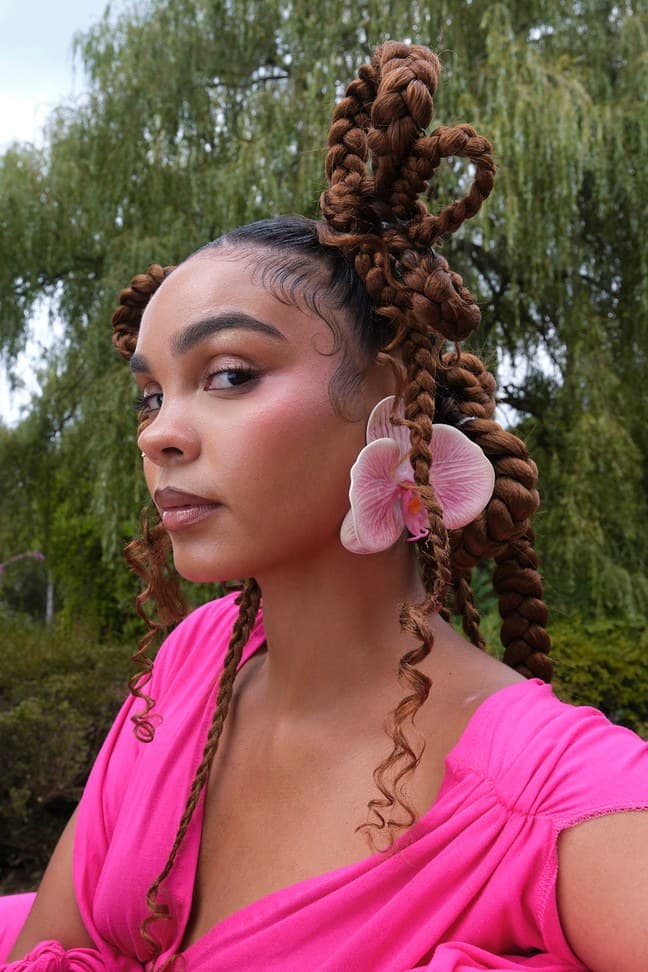 Woman in a pink dress with sculpted braids and an orchid in her hair