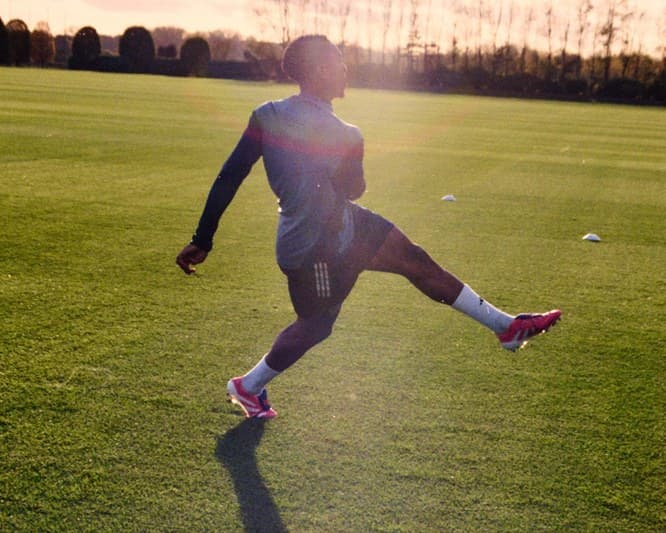 A player mid-stride on a pitch at sunset