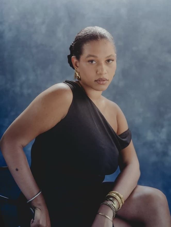 Portrait of a woman in a black one-shoulder dress against blue