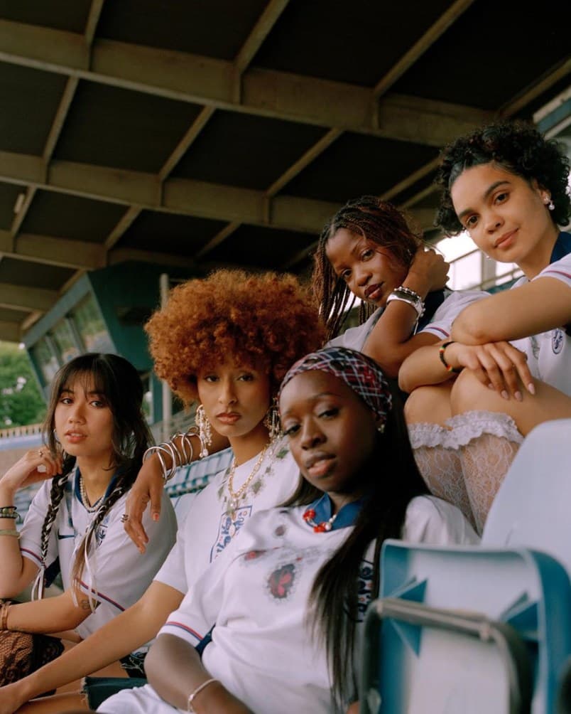 A group of women in football shirts sitting together in the stands
